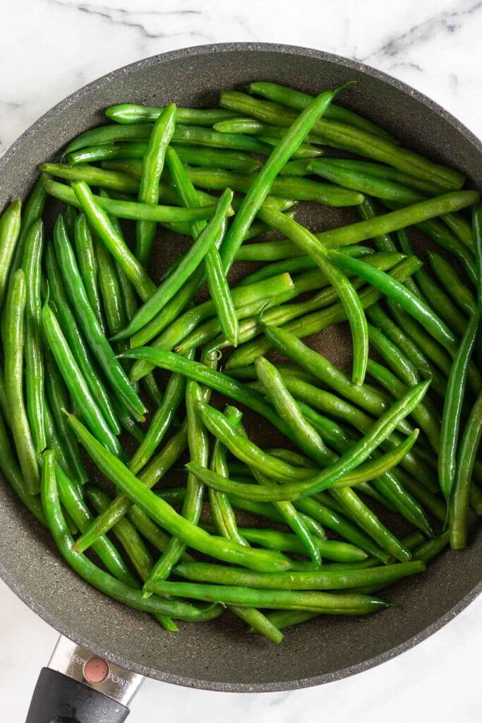 Large skillet with sautéed green beans.