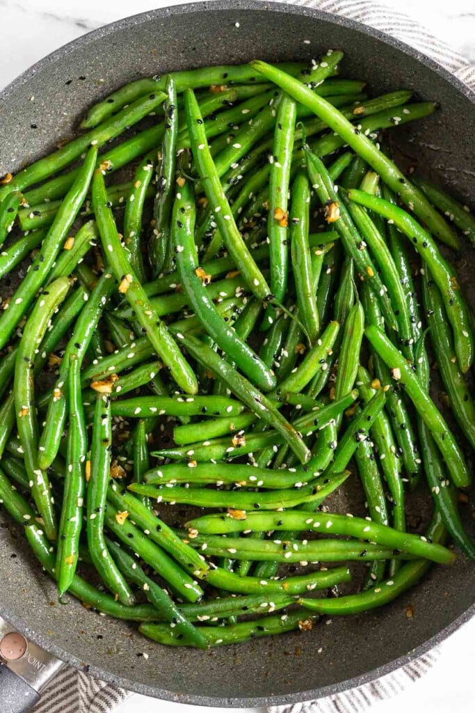 Garlic green beans with garnished with sesame seeds in a large skillet.