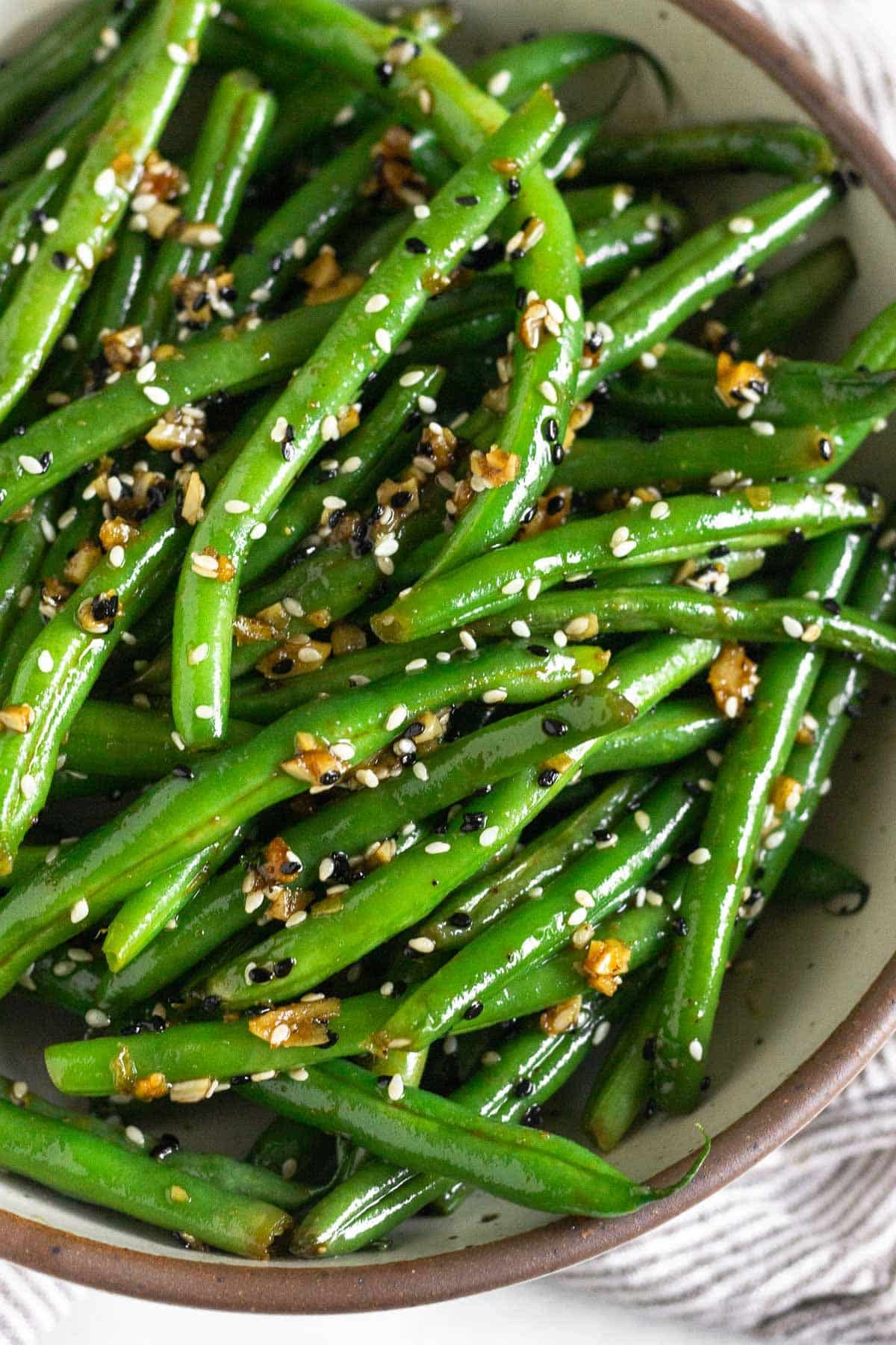 Sesame green beans with garlic in a large white bowl.