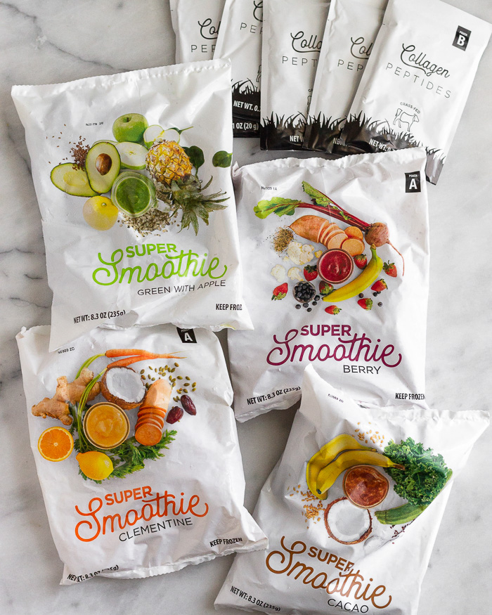 Four packs of Smoothie Box flavors along with 4 packets of collagen on a white counter top.