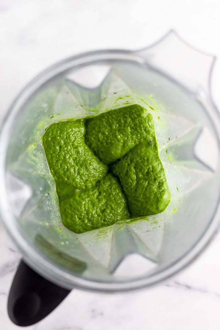 Green smoothie blended up inside a blender.
