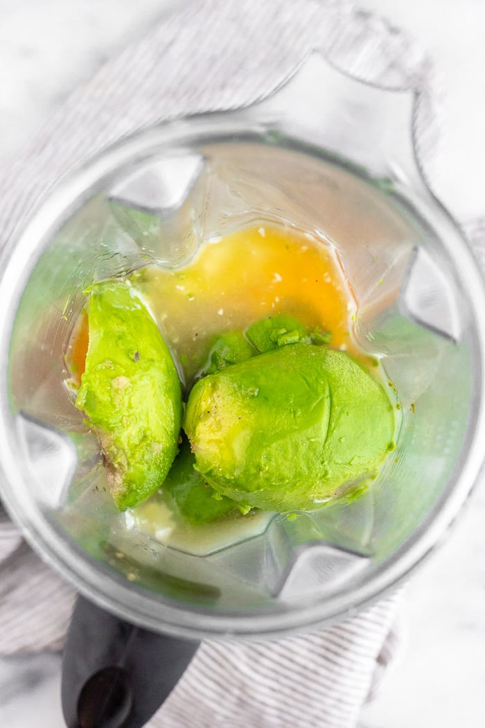 Blender filled with yogurt, avocados, lime juice, honey, and salt not yet blended.