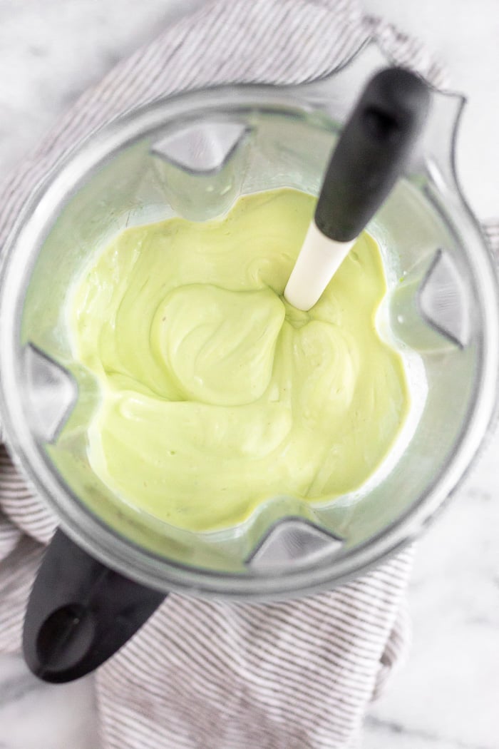 Blender filled with a blended mixture of yogurt, avocados, lime juice, honey, and salt.