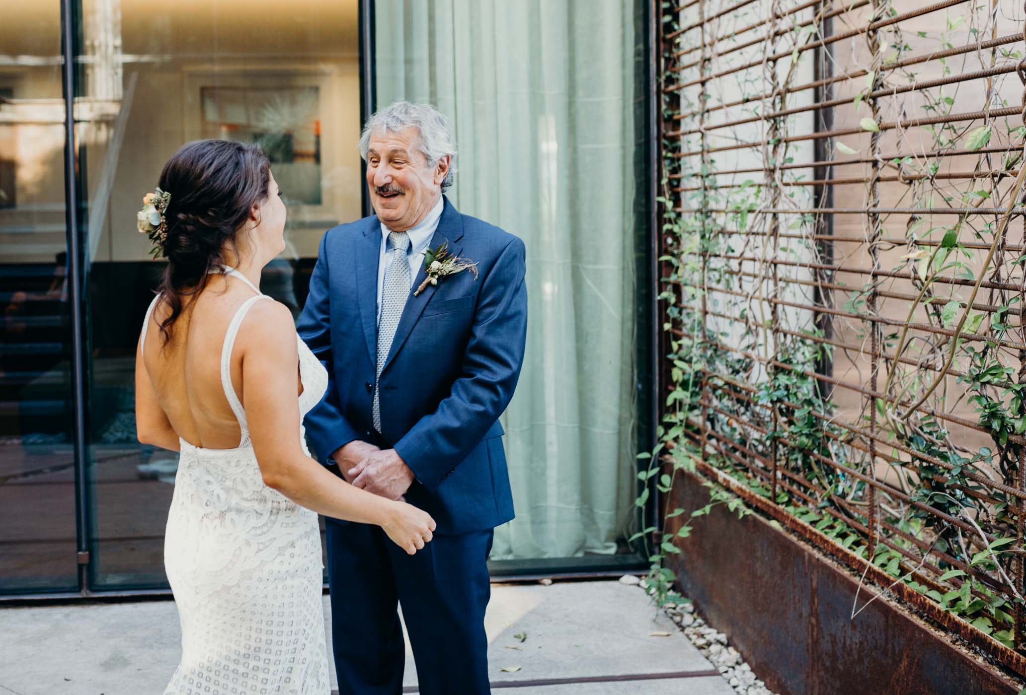 Daughter coming up to her dad on her wedding dad before the fruit look with her husband.