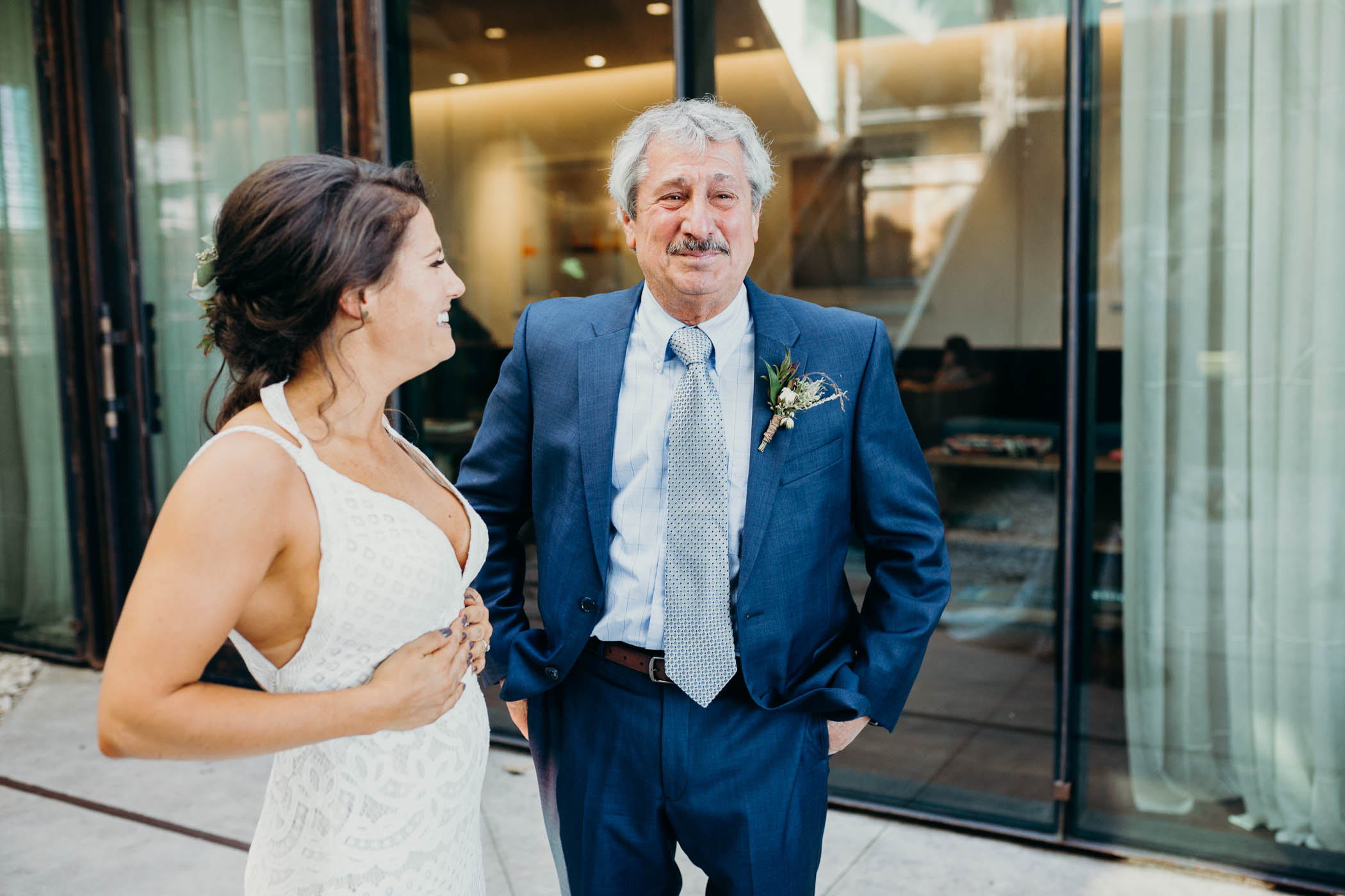 A daughter laughing while a dad is not trying to her on his daughter's wedding day.