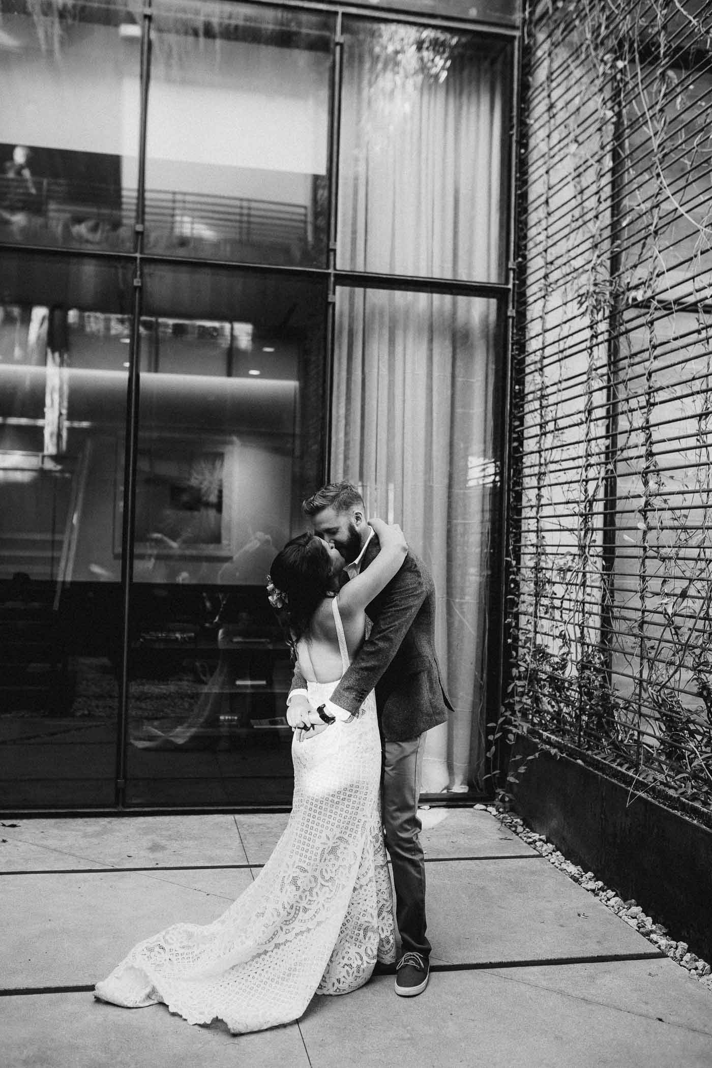 Black and white picture of a bride and groom hugging and missing during their first look at their wedding.