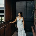 Girl in a lace boho wedding dress holding up one side of it. She is wearing vans.