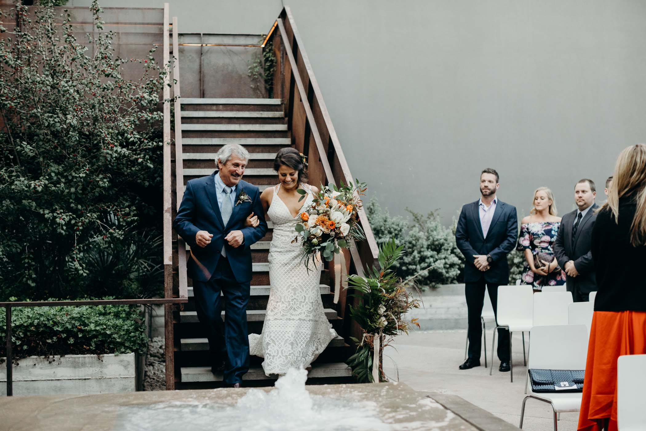 Bride and her dad walking down a staircase to the the alter.