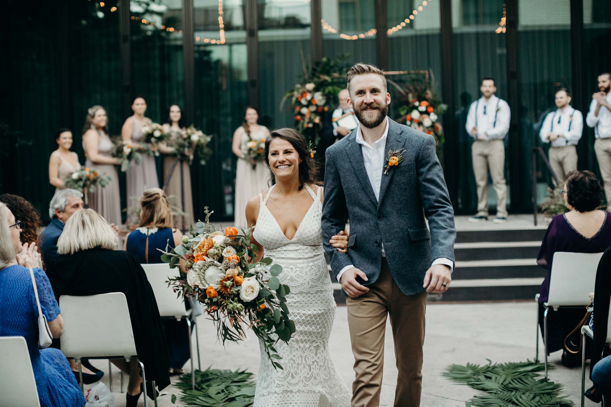 Bride and groom just married walking down the aisle.Bride is wearing a lace boho dress.