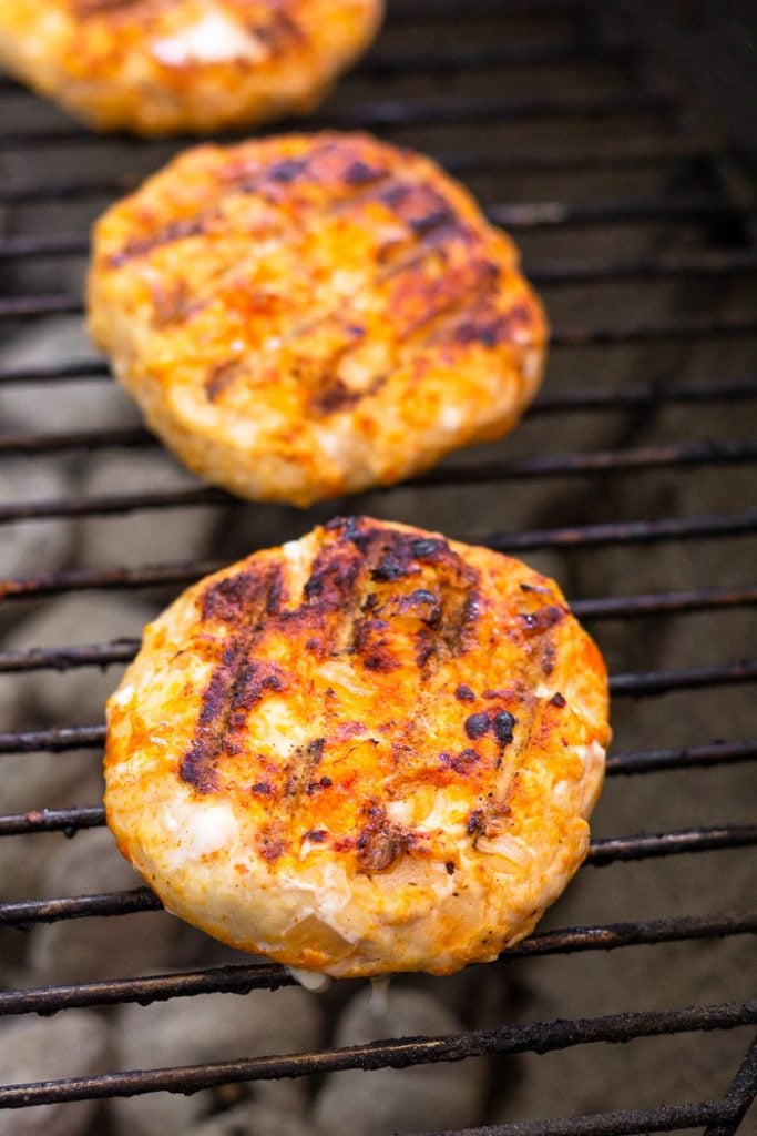 Spicy grilled chicken burgers on a grill.