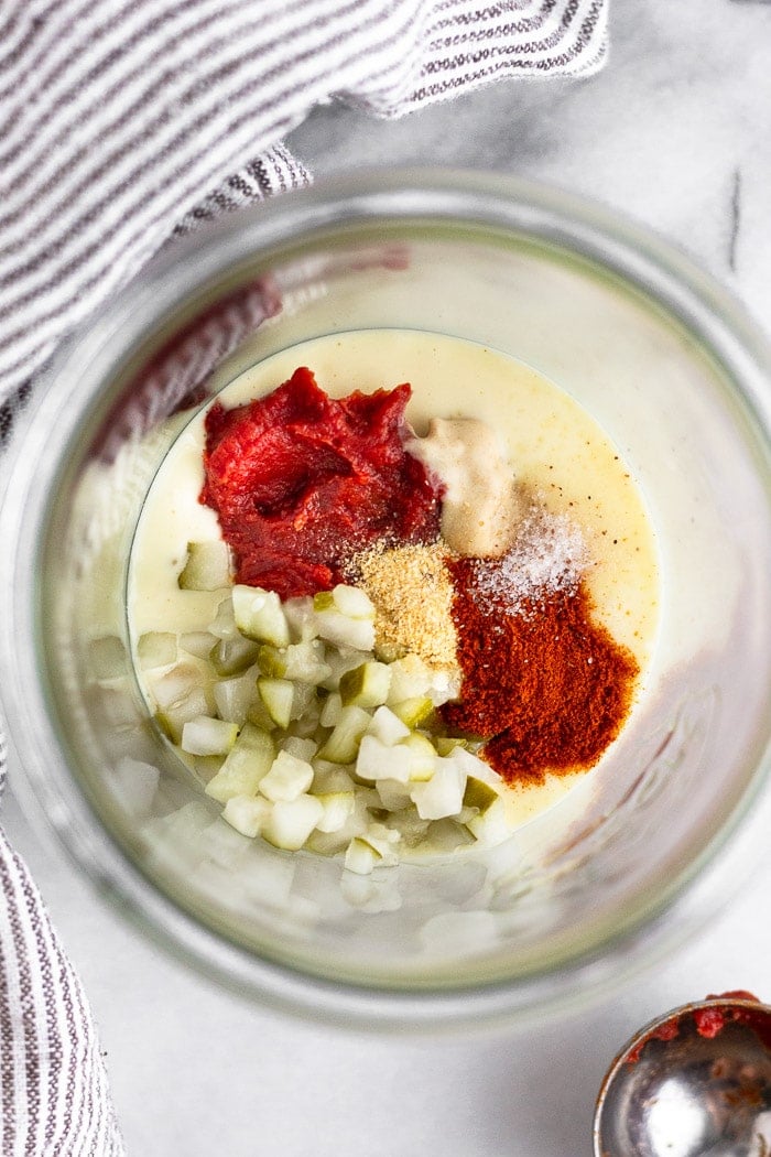 Glass jar filled with mayo, tomato paste, spices, mustard, and chopped pickles.