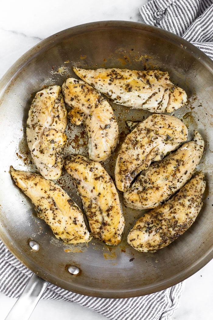 Pan fried chicken tenders in a stainless steel pan.