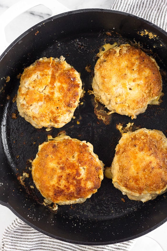 Four cooked Mahi Mahi burger patties in a cast iron skillet.
