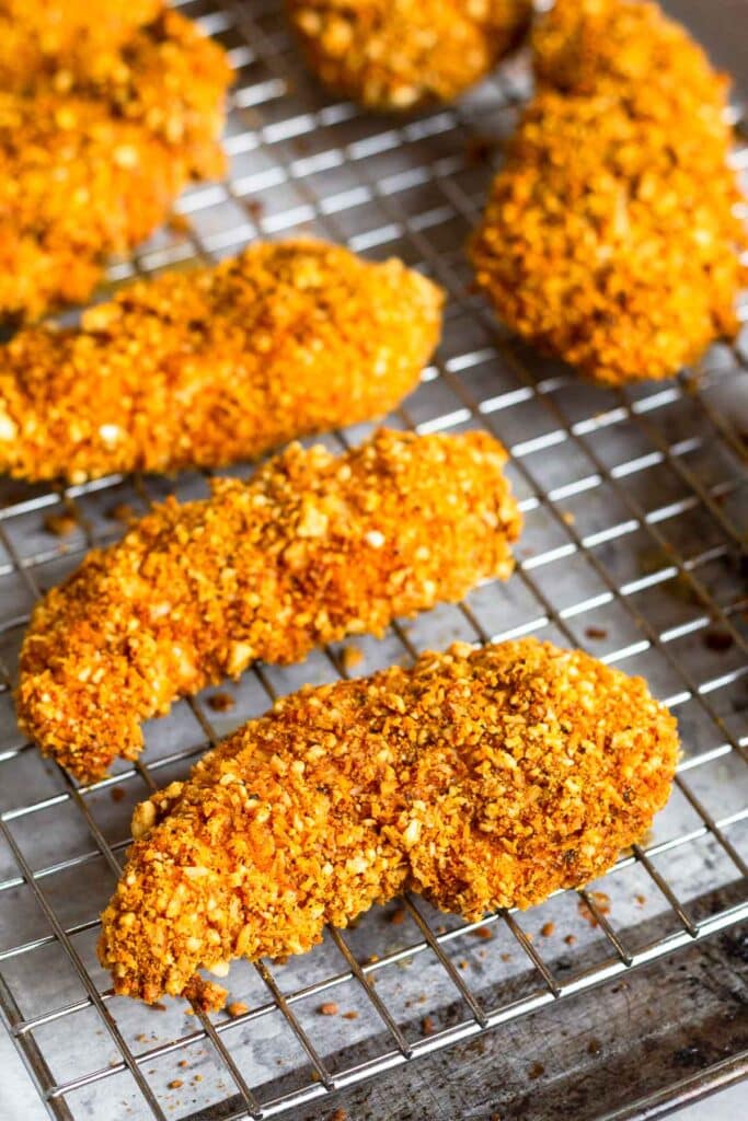 Buffalo chicken tenders on a wire cooling rack on a baking sheet.