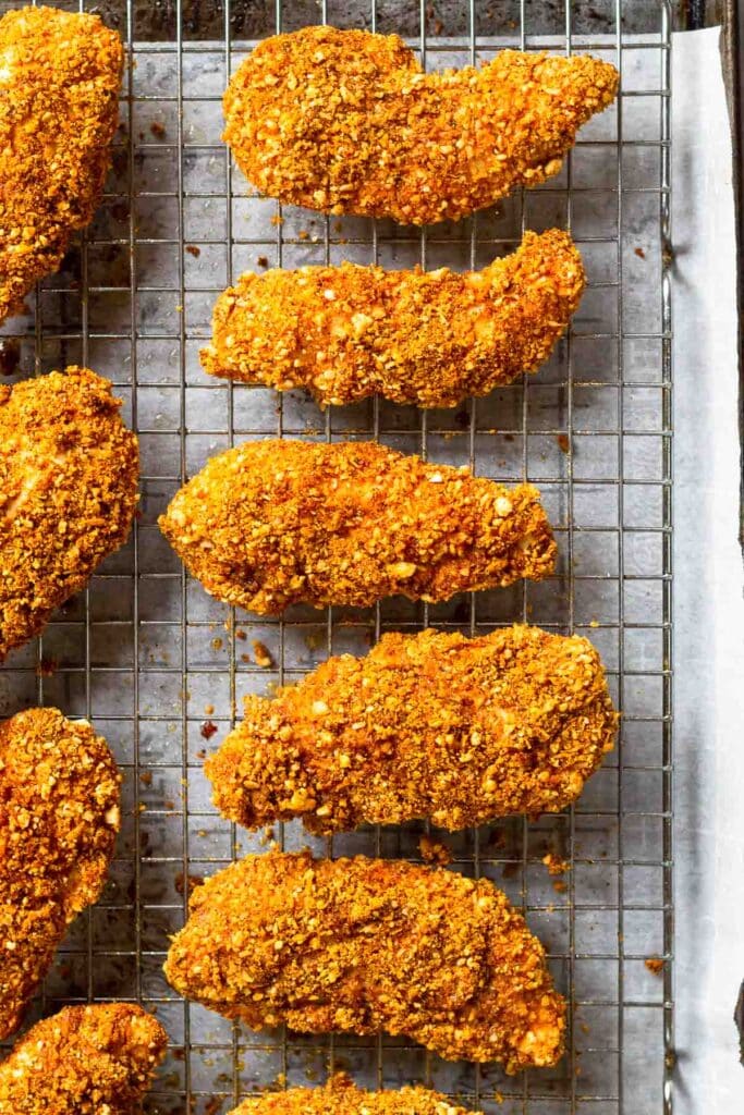 Overhead shot of buffalo chicken tenders on a wire cooling rack on a baking sheet.