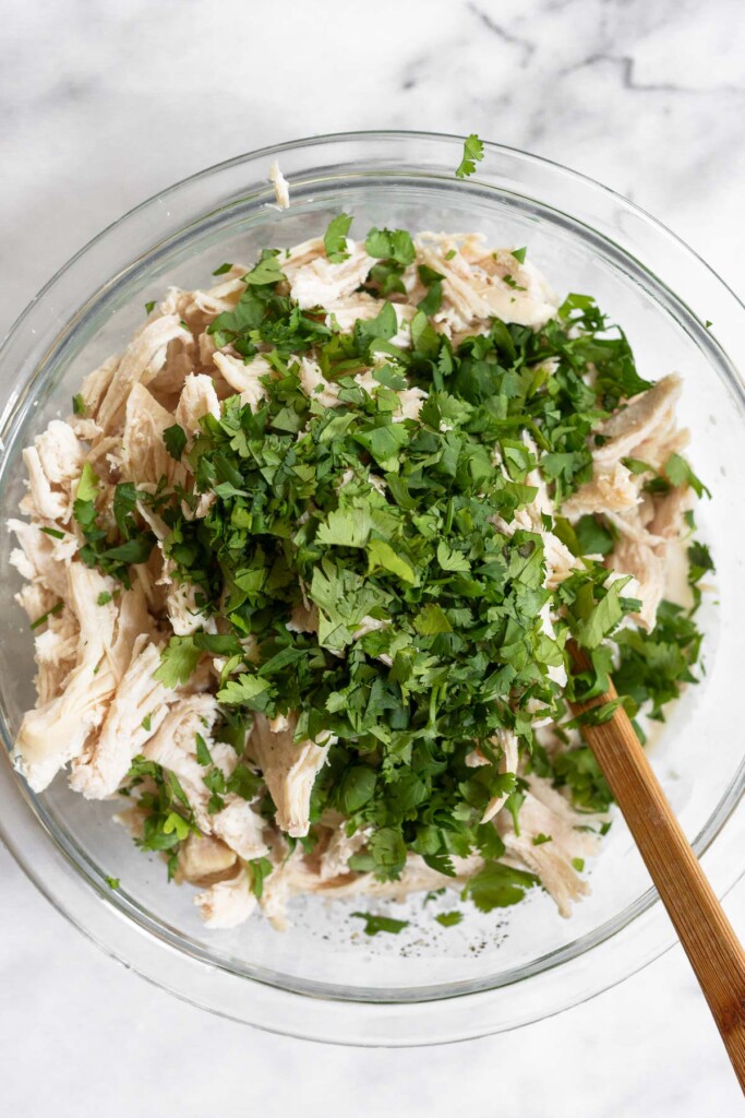 Shredded chicken with a cilantro overtop it in a large bowl.