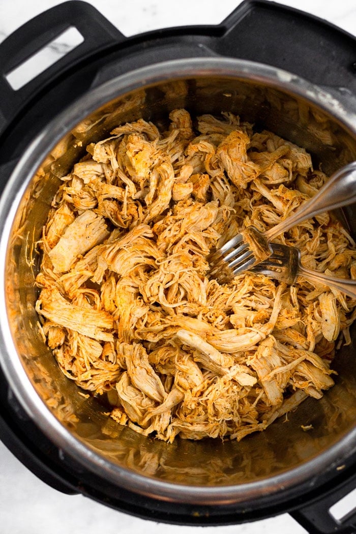 Instant Pot Buffalo Chicken in a pressure cooker with 2 forks in it.