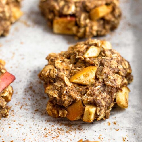 Apple cinnamon protein cookies sprinkled with cinnamon on a baking sheet.