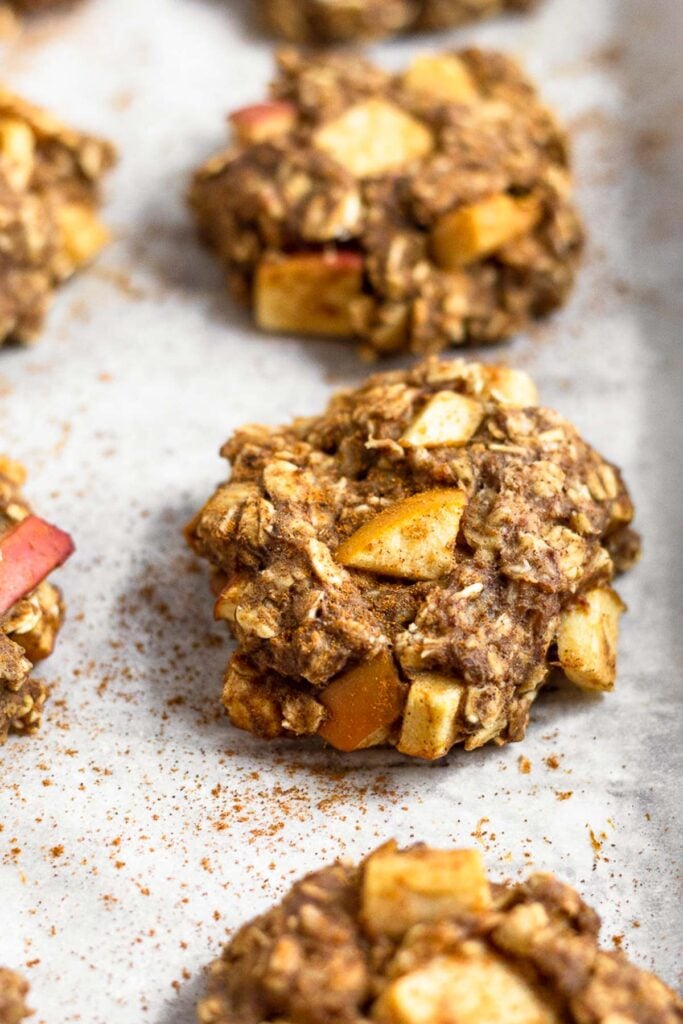 Apple cinnamon protein cookies sprinkled with cinnamon on a baking sheet.