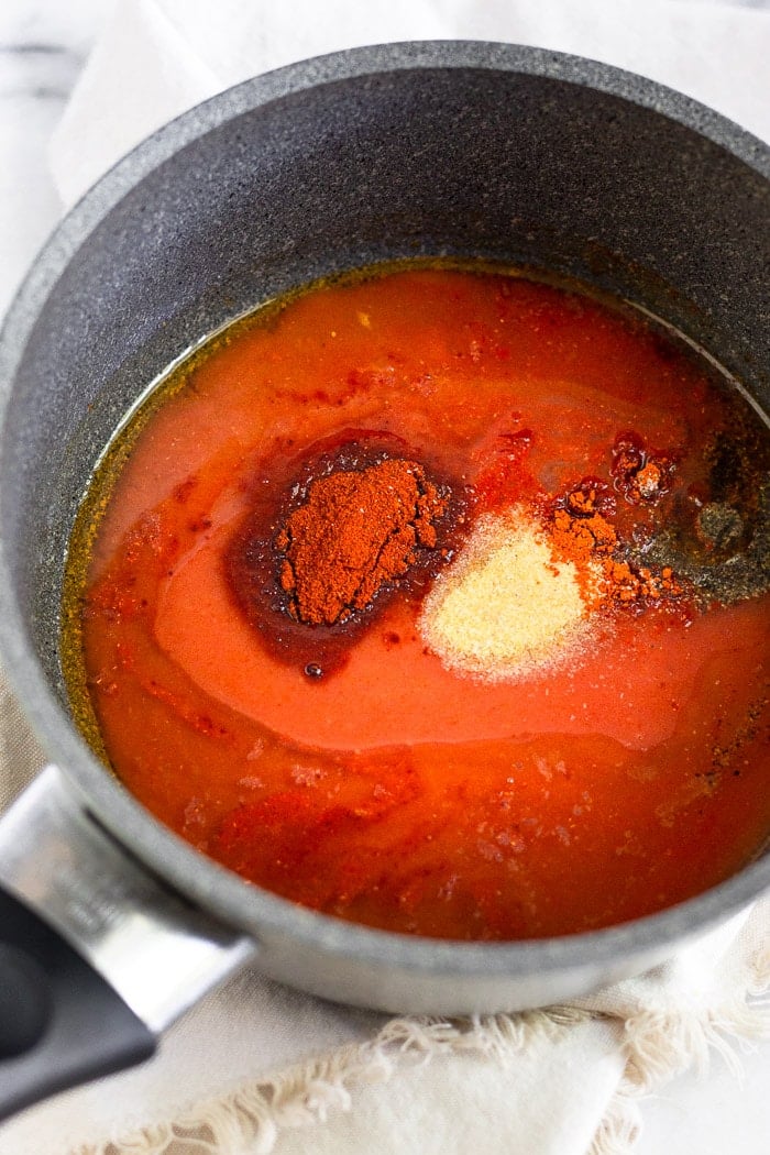 Small sauce pan filled with hot sauce. ghee, and spices.