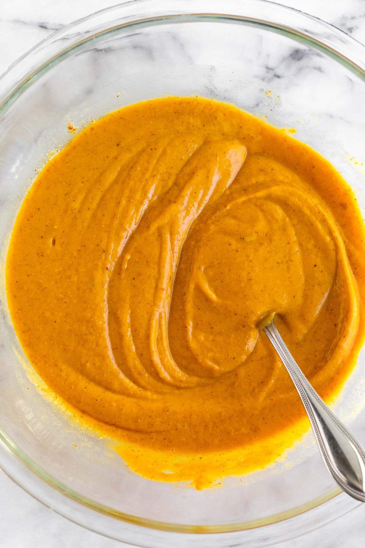 Bowl filled with a pumpkin batter with a fork in it.