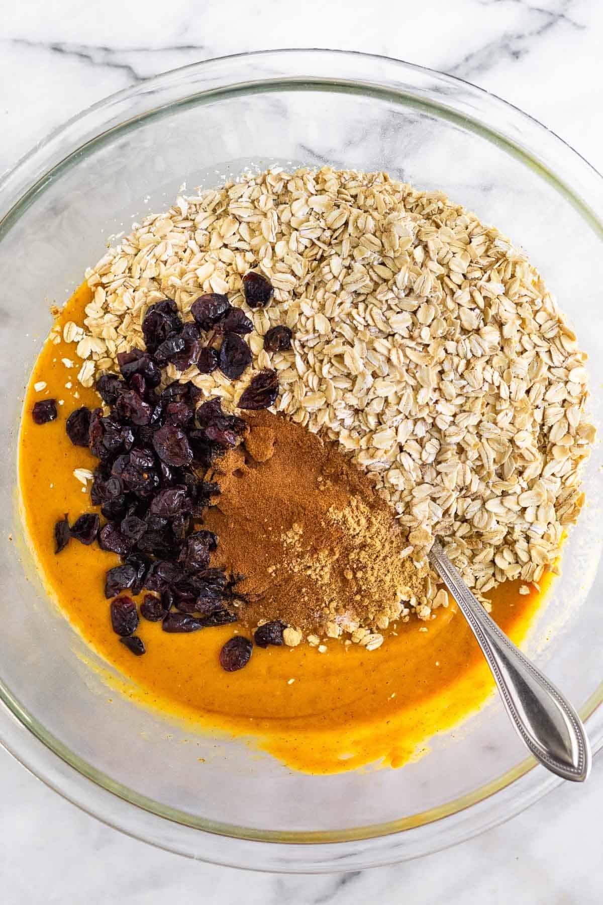 Large bowl with a pumpkin mixture topped with rolled oats, dried cranberries, and spices.