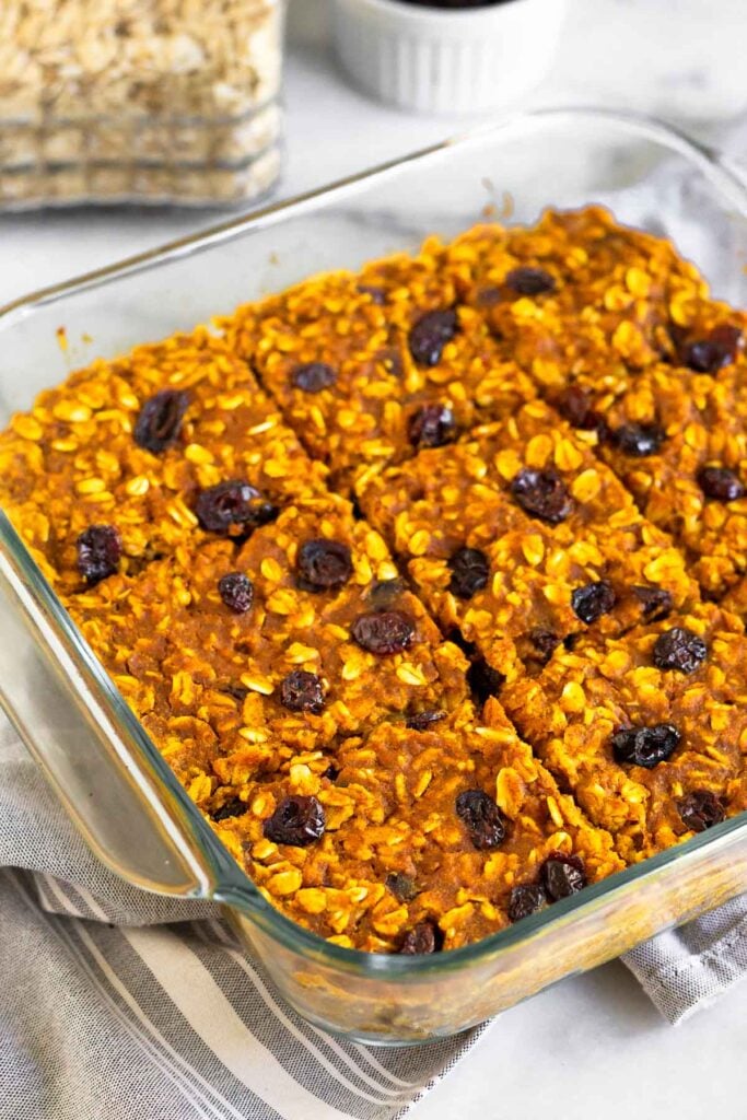 Pumpkin baked oatmeal in a baking dish on a kitchen towel.