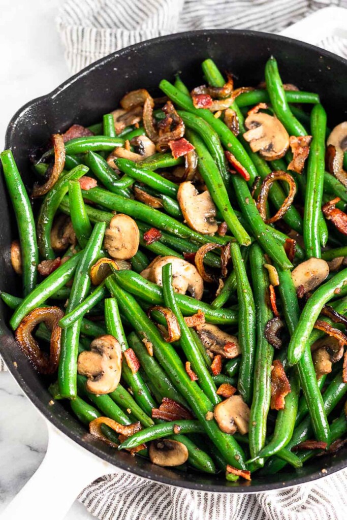 Sautéed green beans, mushrooms, onions, and bacon in a large cast iron skillet.