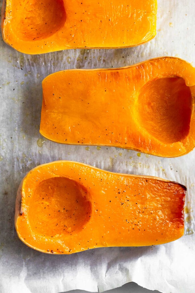 A baking sheet with roasted butternut squash halves on it.