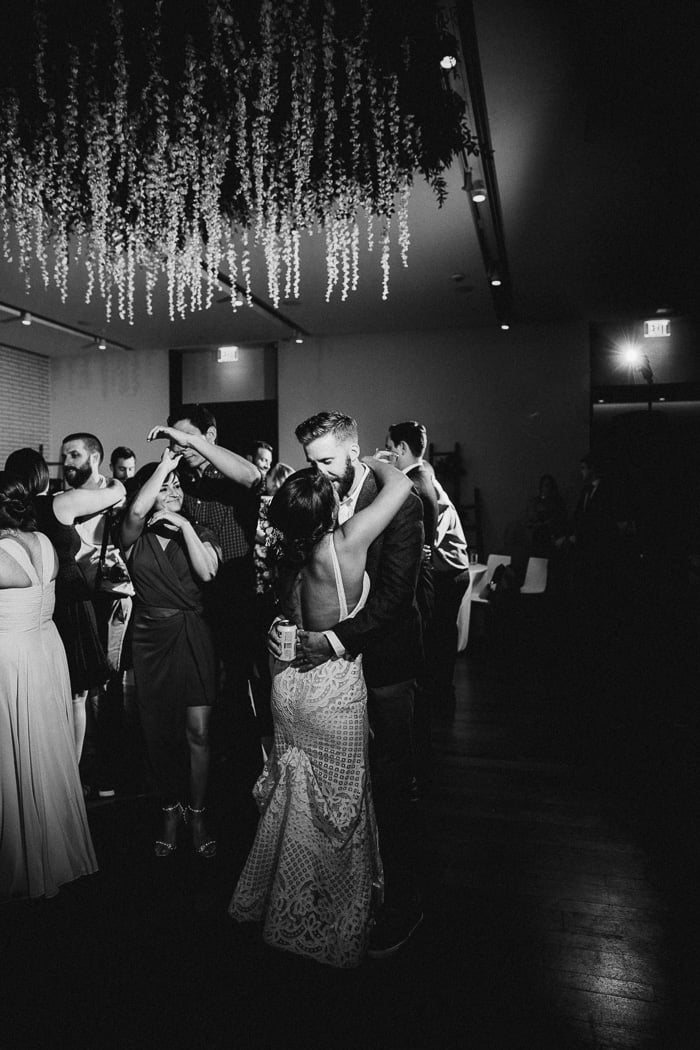 Bride and groom slow dancing on their wedding day with more people dancing behind them.