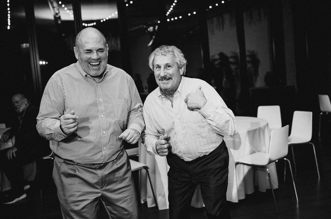Two older guys dancing and laughing at a wedding.