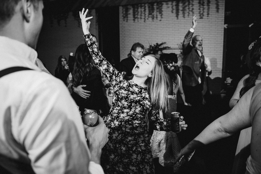 Girl with her hand in the air signing and dancing at a wedding.