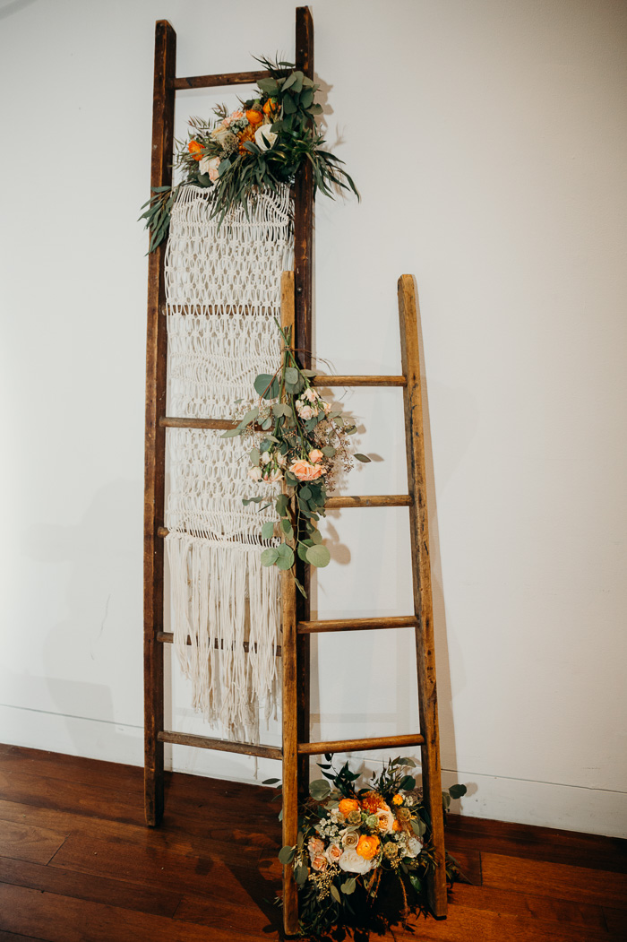 Two ladders decorated with flowers and a macrame hanging.