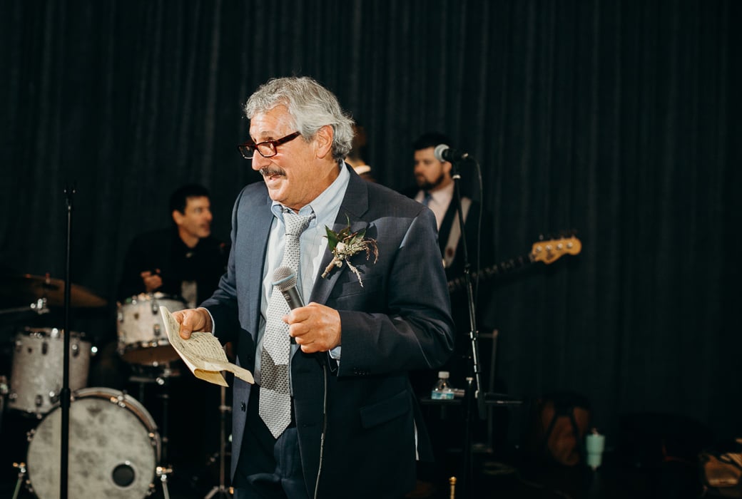 Father in a suit giving a speech at a wedding.