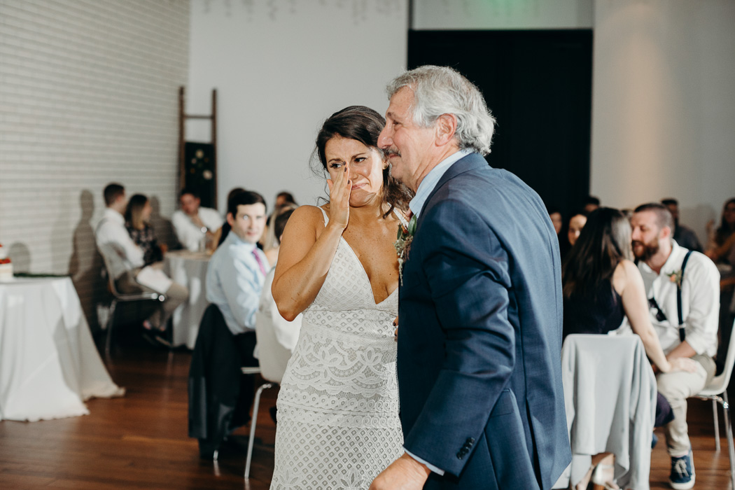 Bride wearing a boho wedding dress tearing up about to hug her dad.