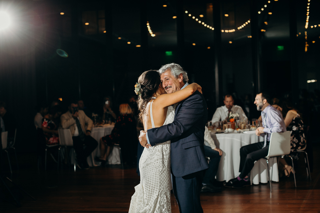 Father and daughter doing their dance at a wedding. They are happily embracing and smiling.