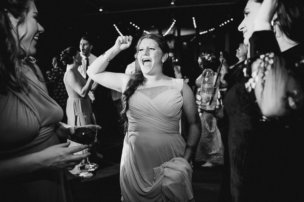 Girl with her fist in the air in the the middle of the dance floor singing.