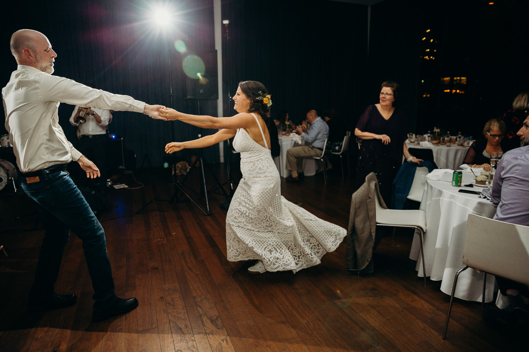 Bride dancing at her wedding with an older man. He is pulling her towards him and her dressing is flying back.