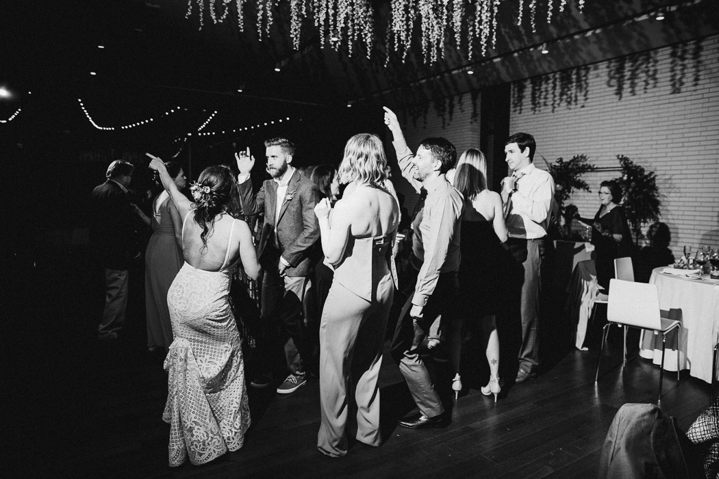 Group of people dancing at a wedding with the bride and groom.