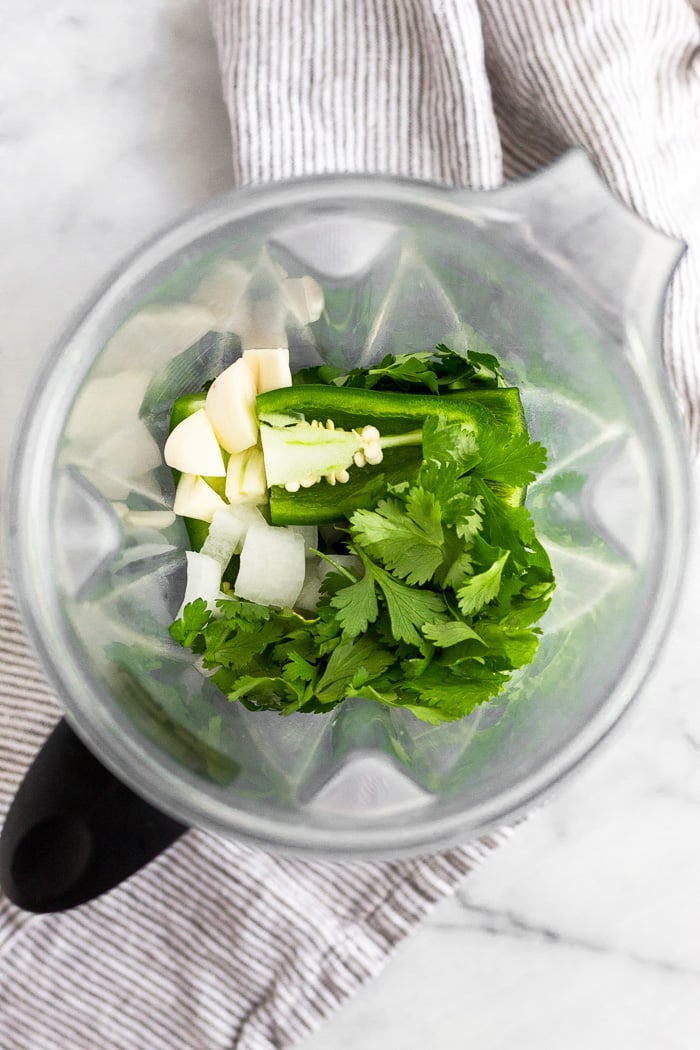 Blender fill of cilantro, parsley, garlic, jalapenos, and onion.