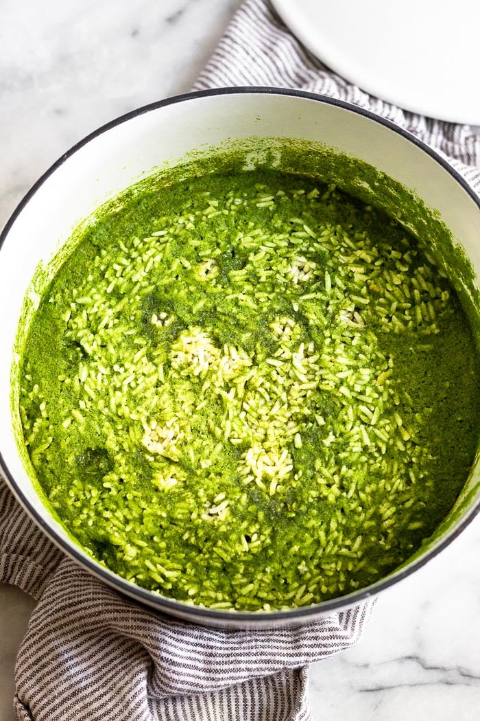 Large white dutch oven filled with cooked arroz verde that has some of the green broth sitting on top.