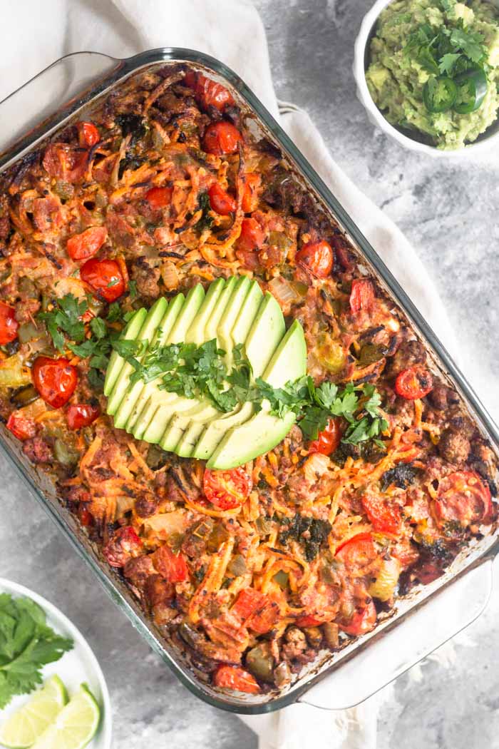 Beef taco casserole topped with slice avocado and cilantro.