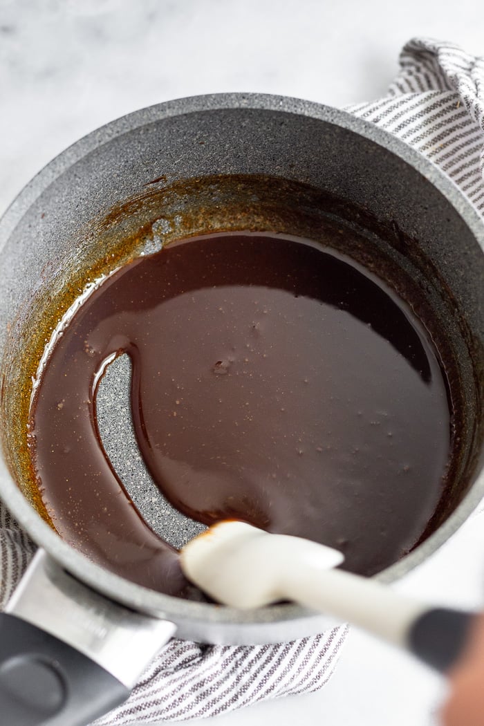 Whiskey glaze in a small sauce pan with a spatula running through it leaving a clean line.