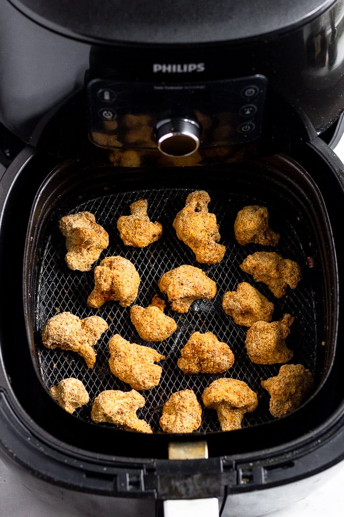Air fryer filled with cooked crispy breaded cauliflower in it.