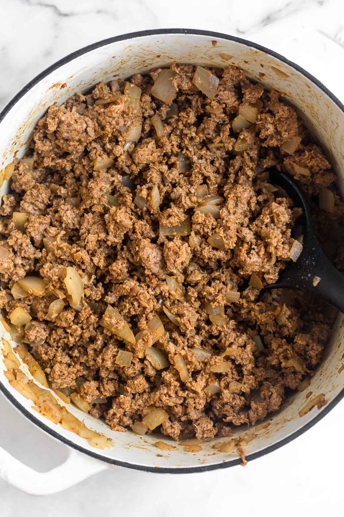 Large dutch oven filled with browned ground buffalo.