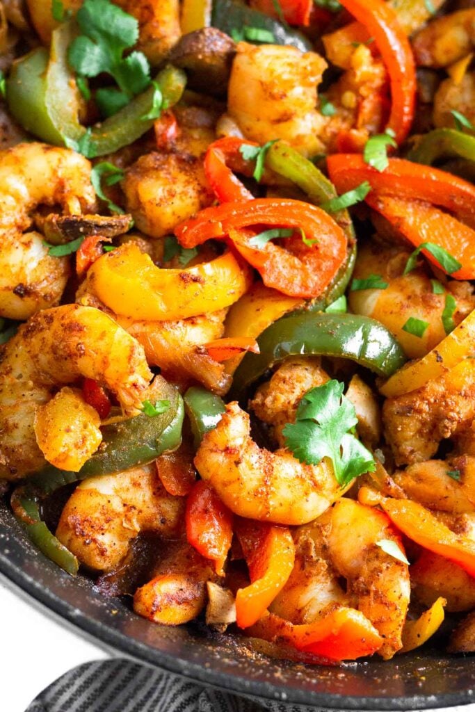 Close up of shrimp fajitas in a pan garnished with cilantro.