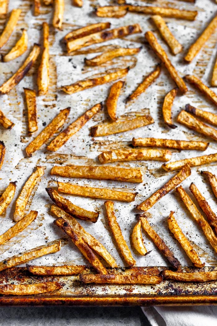 Baking sheet with baked turnip fries spread out on it fresh out of the oven.