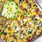 Ground turkey spaghetti squash casserole topped with ranch dressing, parsley, and sliced avocado. Off to the side of the dish is a bowl of more parsley.
