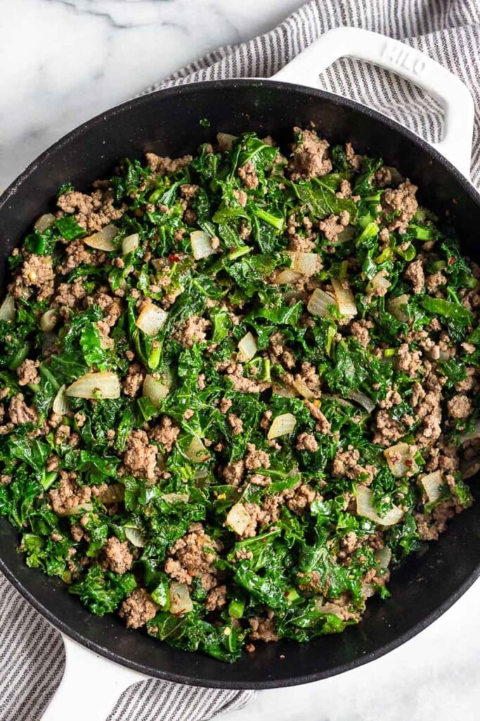 Cast iron filled with sautéed kale ground beef, and onions.