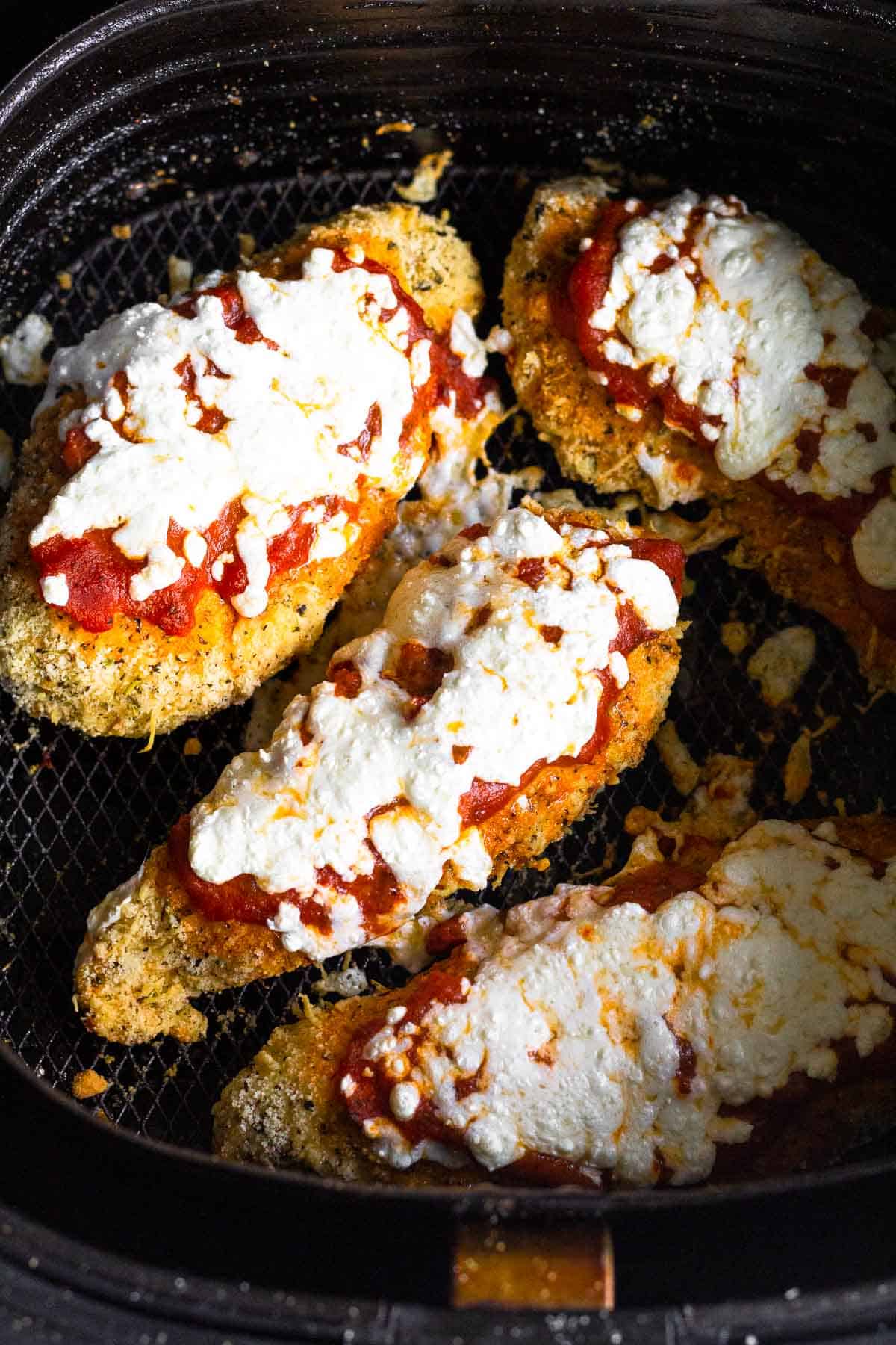 Chicken parmesan in an air fryer basket.